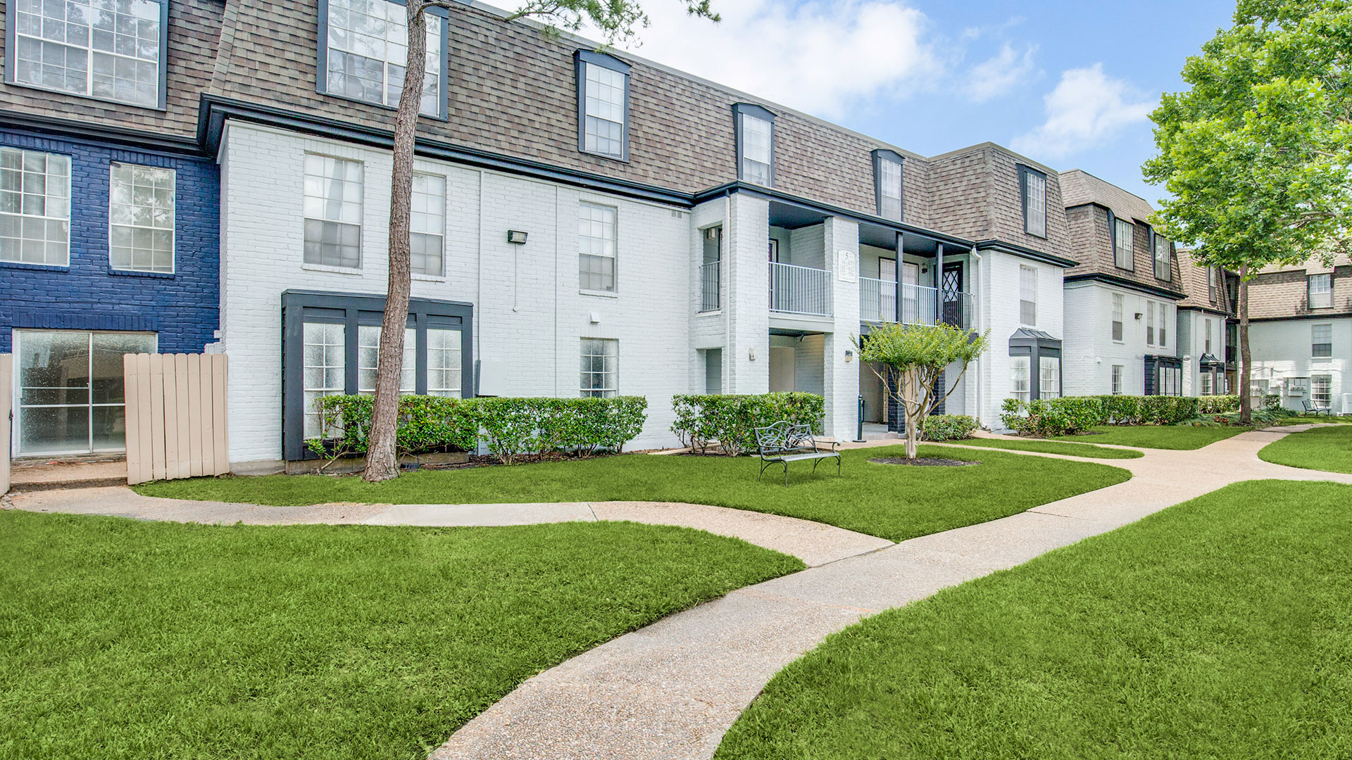 the exterior of an apartment complex with green grass and trees at The WESTON