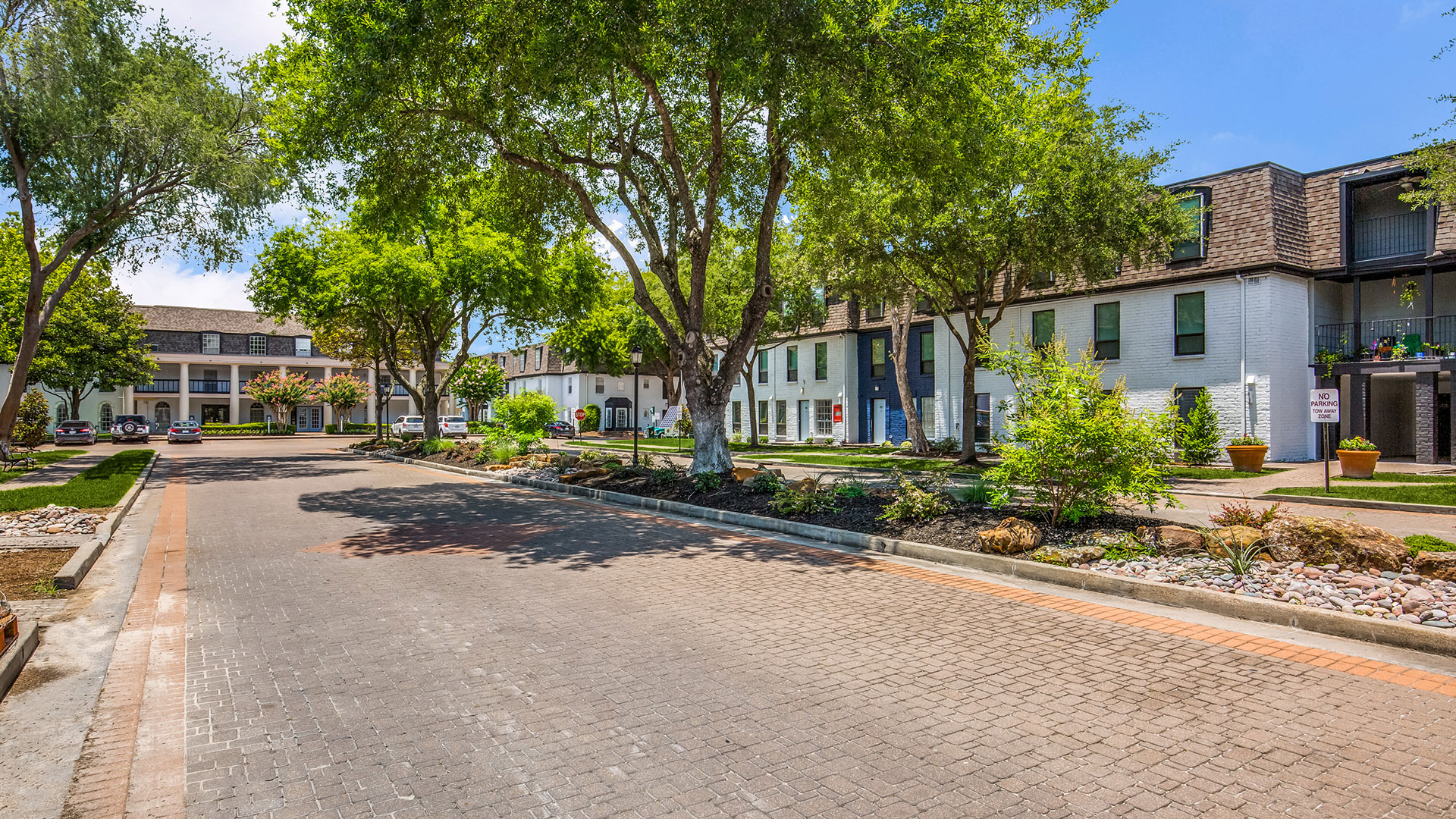 the street in front of a residential complex with trees and bushes at The WESTON