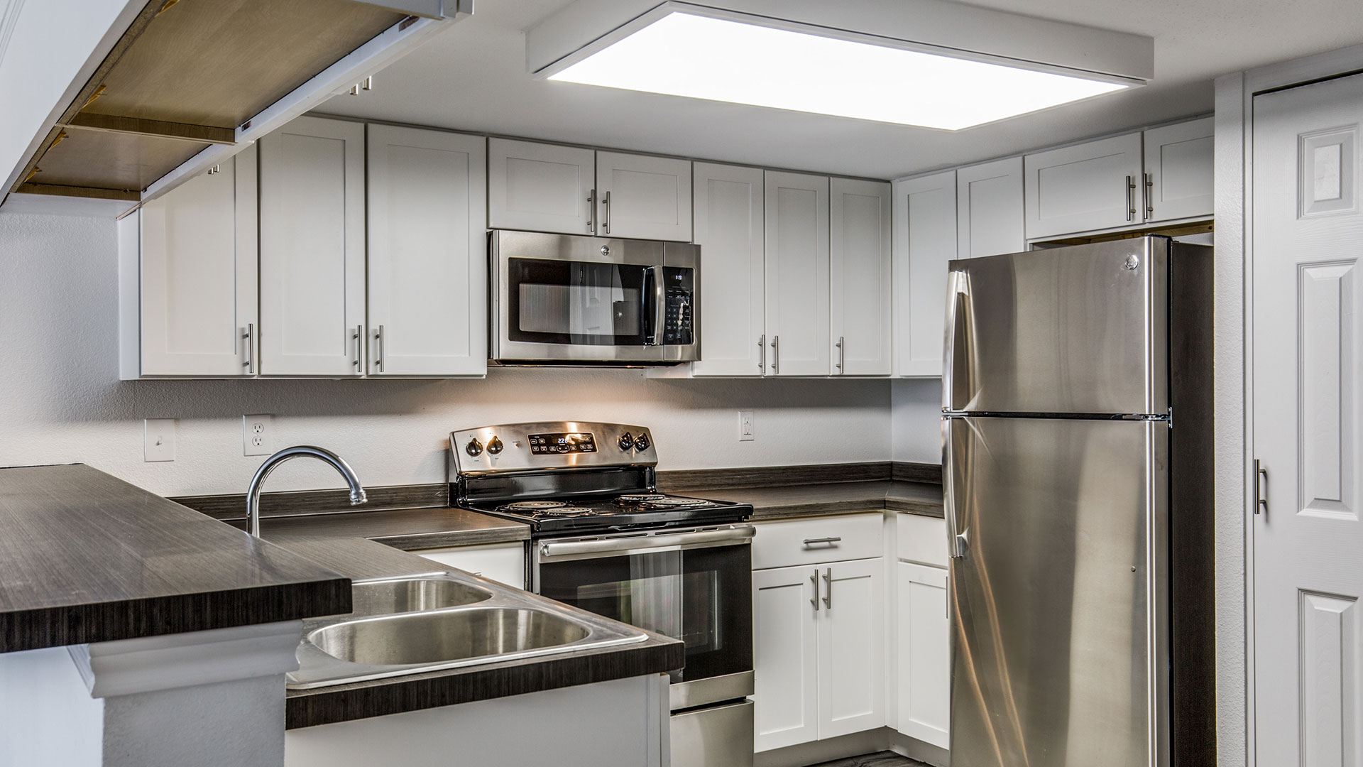 a kitchen with stainless steel appliances and white cabinets at The WESTON
