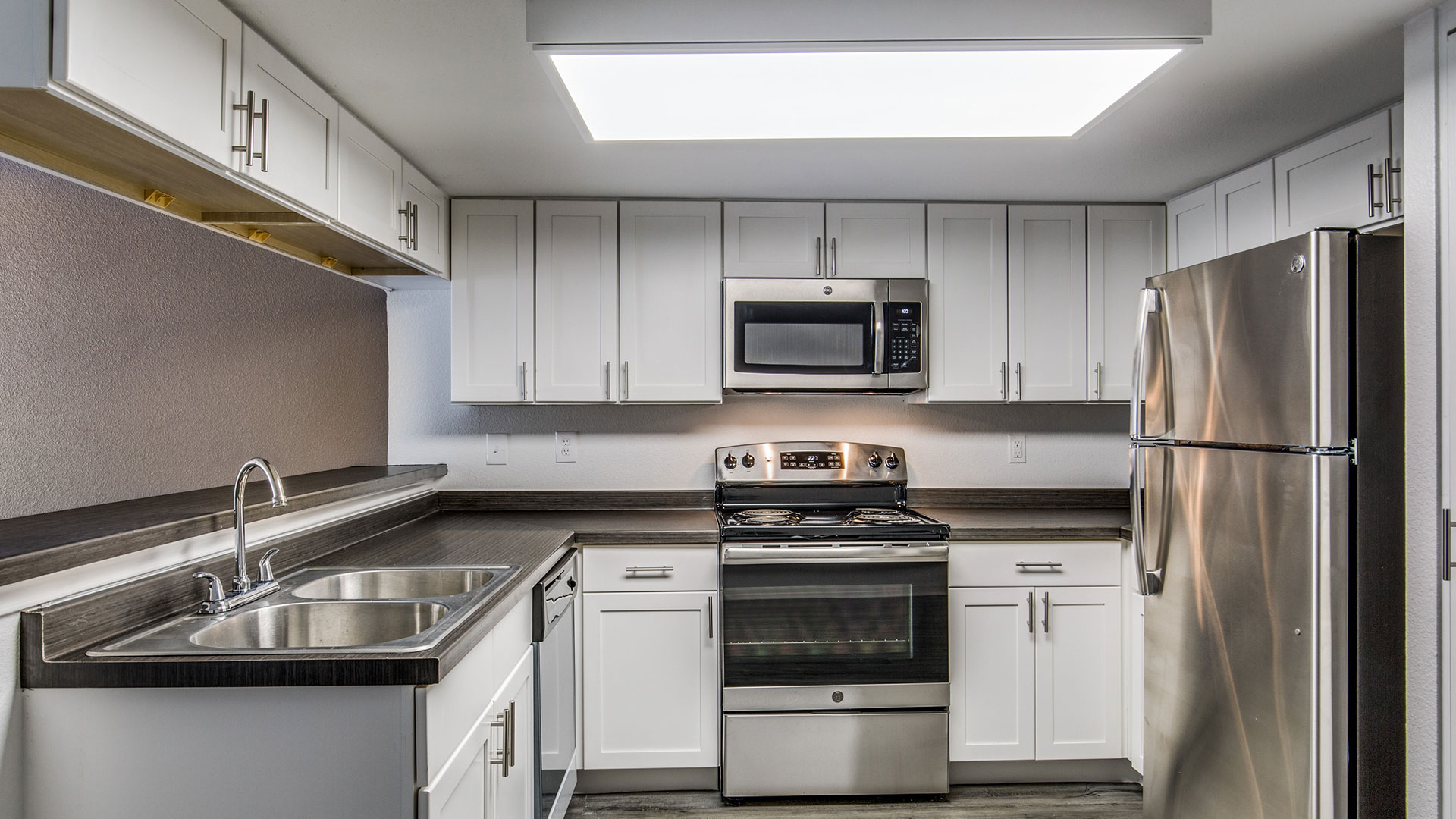 a kitchen with stainless steel appliances and white cabinets at The WESTON