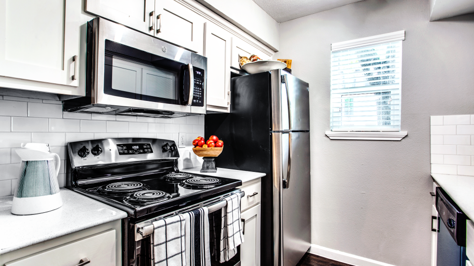 a kitchen with a stove, microwave, refrigerator and sink at The WESTON